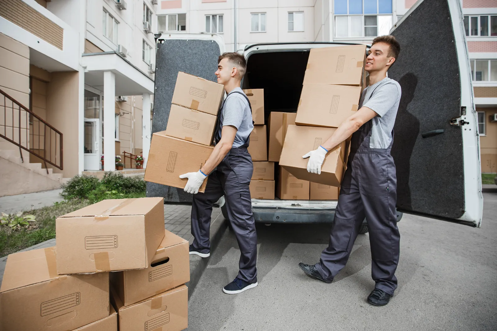 Zwei Umzugshelfer tragen Kartons aus dem Umzugswagen