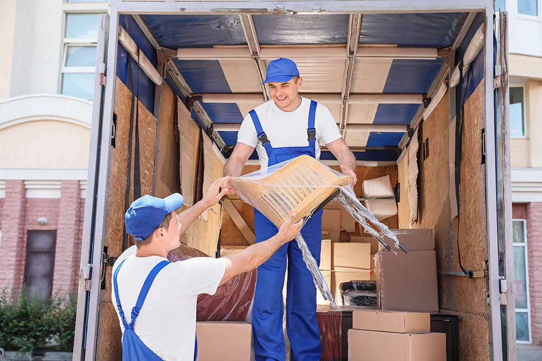 Zwei Umzugshelfer verladen Möbel in den Transporter
